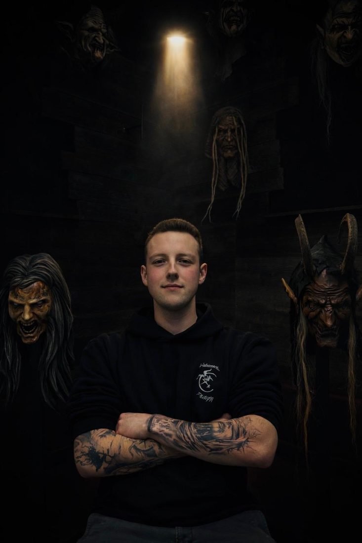 Manuel, Holzmasken Philipps, vor selbstgeschnitzten Krampusmasken