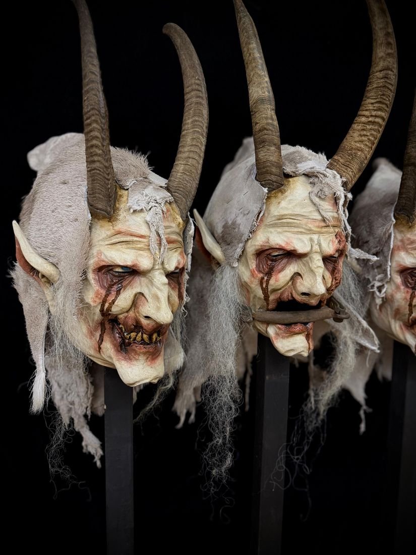 Masken mit hellen Fellhauben und Hörnern